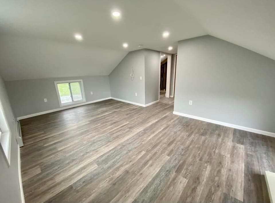 Finished attic addition with gray walls, wood-look flooring, and recessed lighting