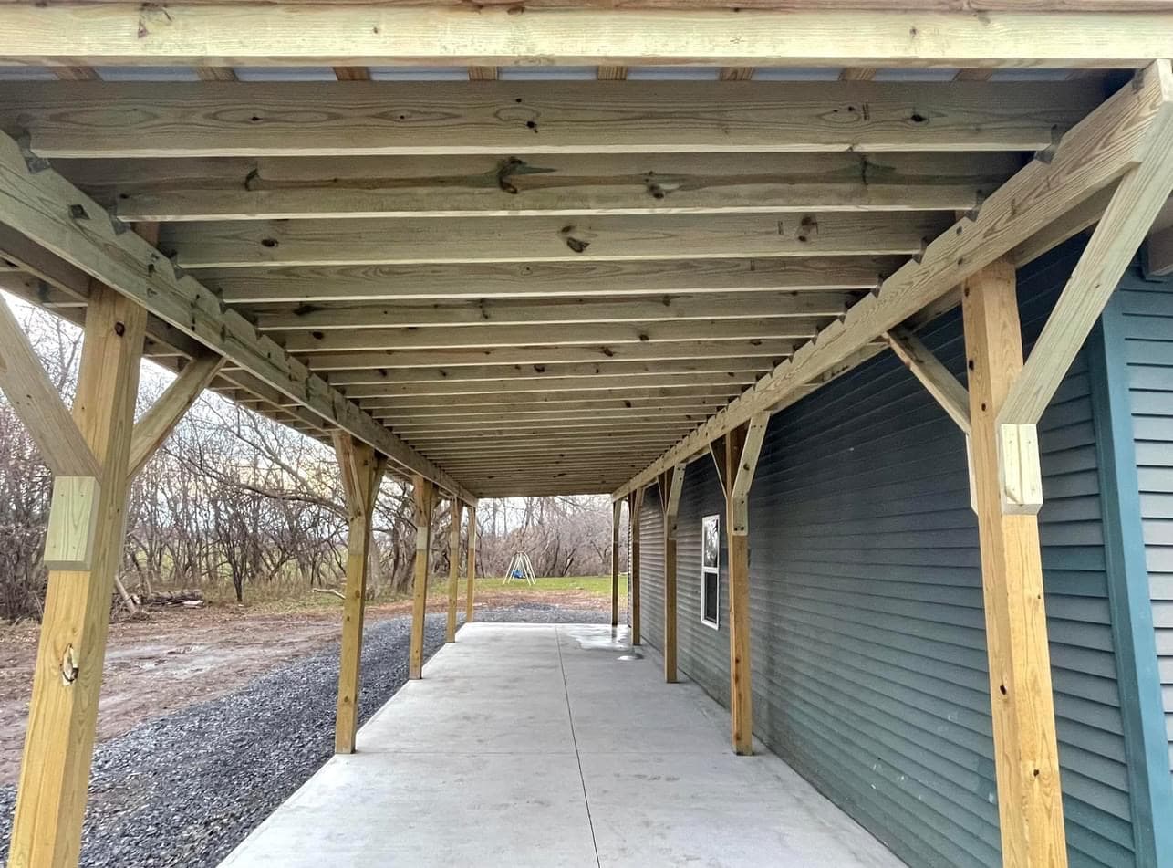 Covered porch addition with wood beam structure and concrete walkway