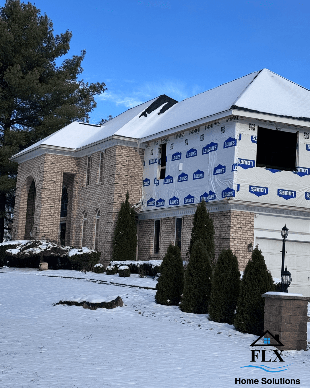 Two-story home addition under construction with Tyvek house wrap and snow-covered roof