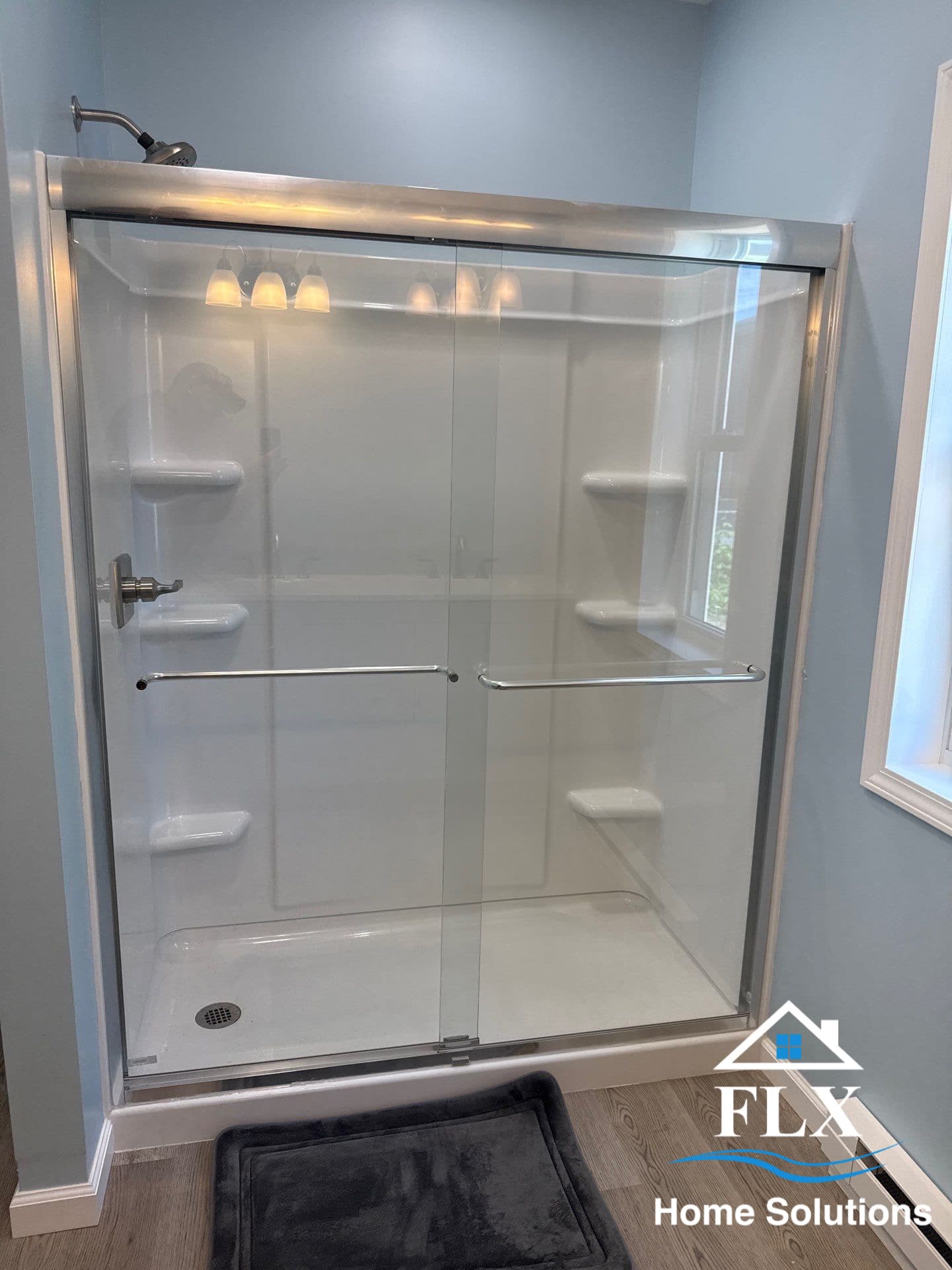 White fiberglass shower enclosure with sliding glass door and chrome fixtures