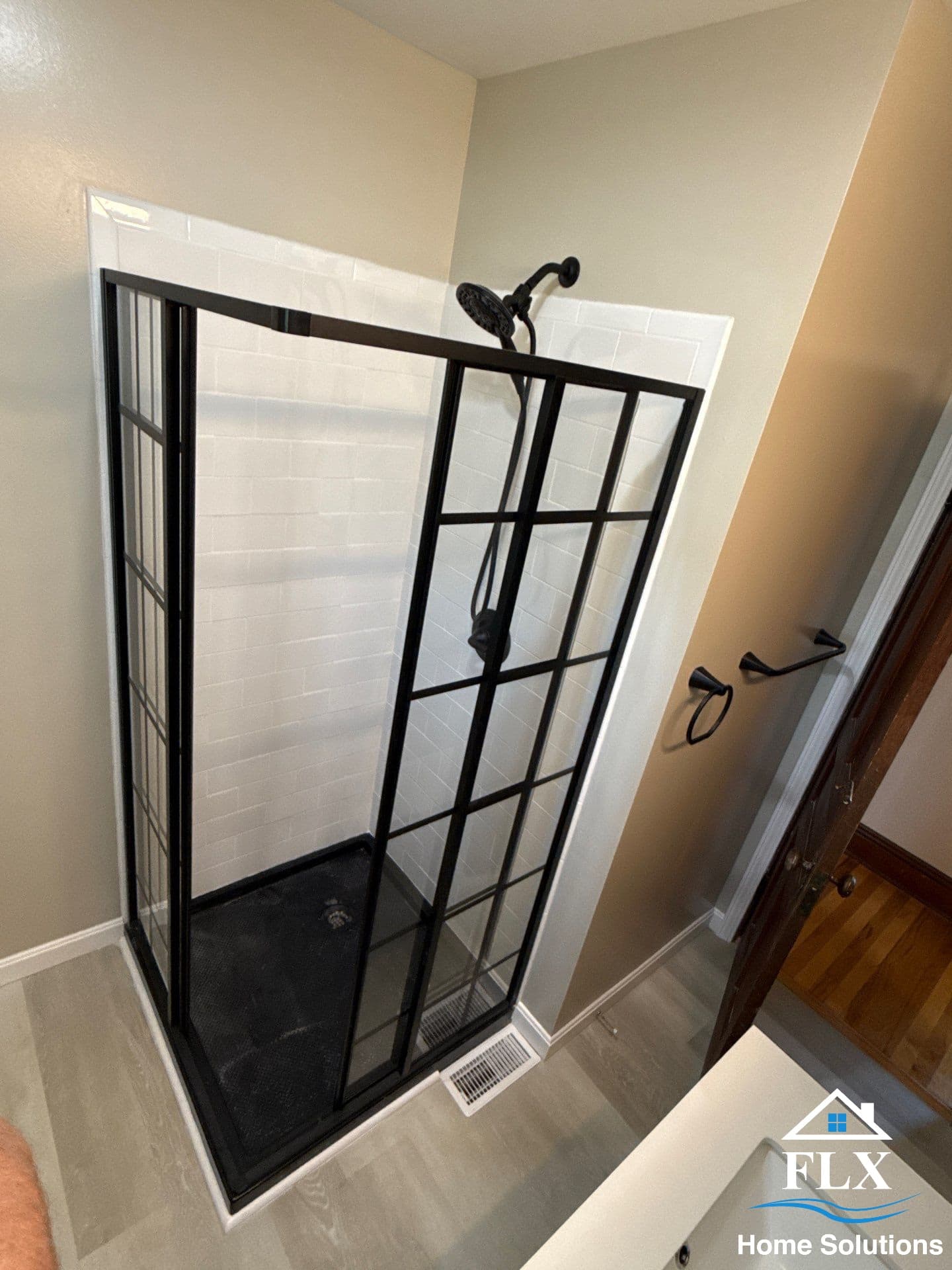 Modern walk-in shower with black gridded glass enclosure and white subway tile