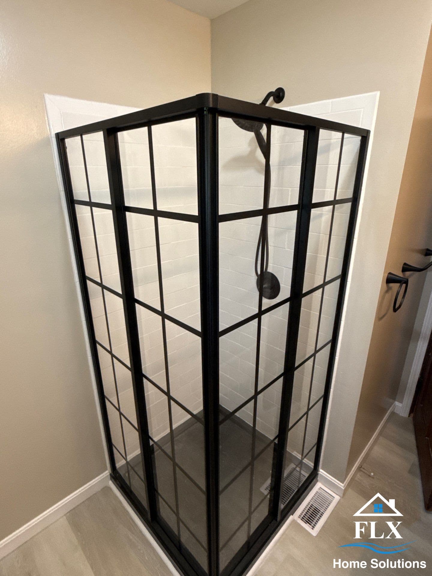 Corner shower with black gridded glass enclosure and white subway tile