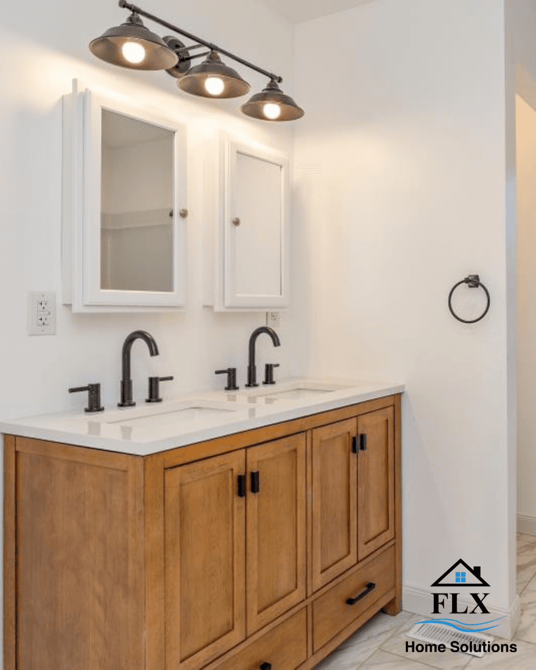 Double vanity bathroom with wood cabinets, white marble countertop, and industrial lighting