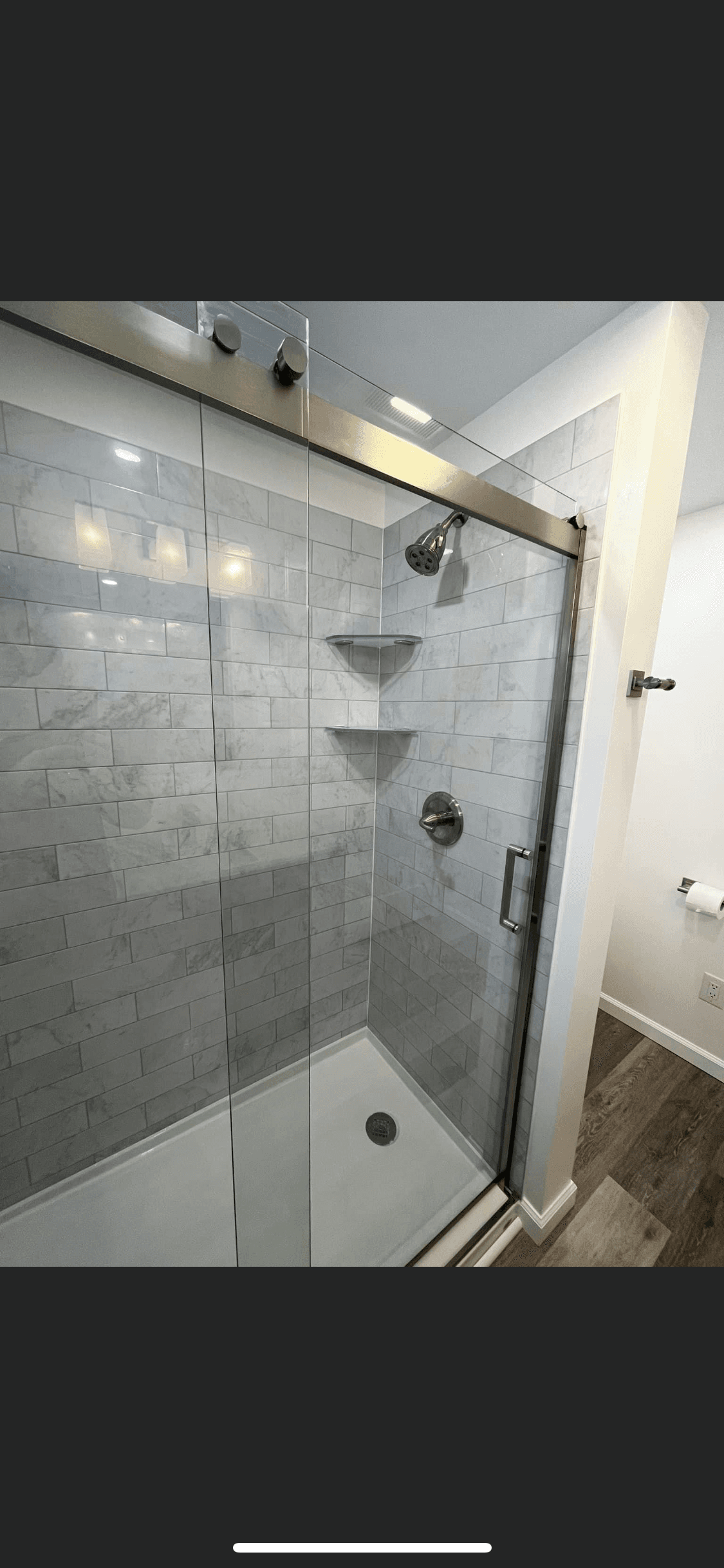 Walk-in shower with glass door, marble subway tile, and built-in shelves