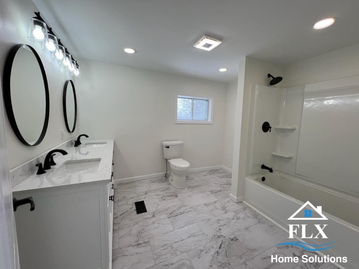 Modern bathroom with double vanity, black fixtures, and marble-look flooring