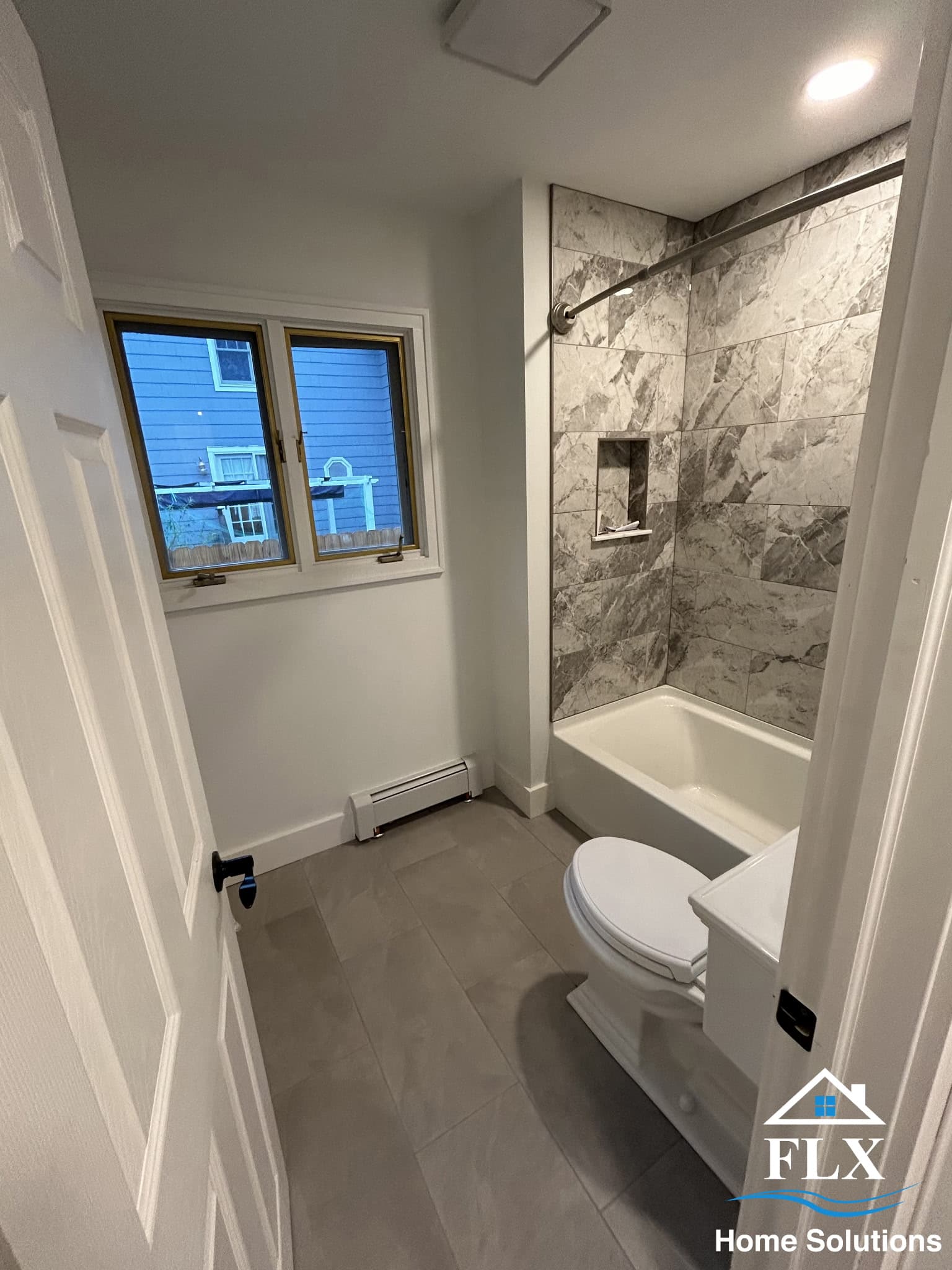 Modern bathroom with gray marble tile shower surround and glass door