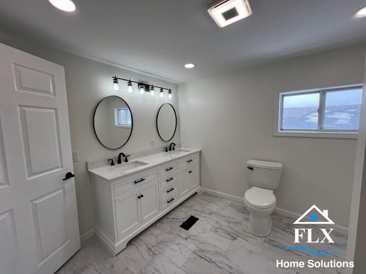 Modern bathroom with white double vanity, round black mirrors, and marble tile flooring