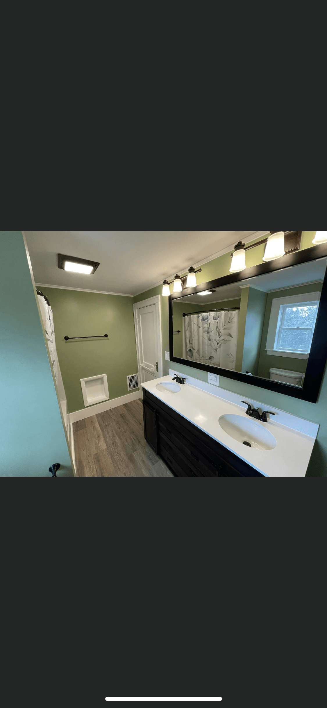 Modern bathroom with green walls, double sink vanity, and wood-look flooring