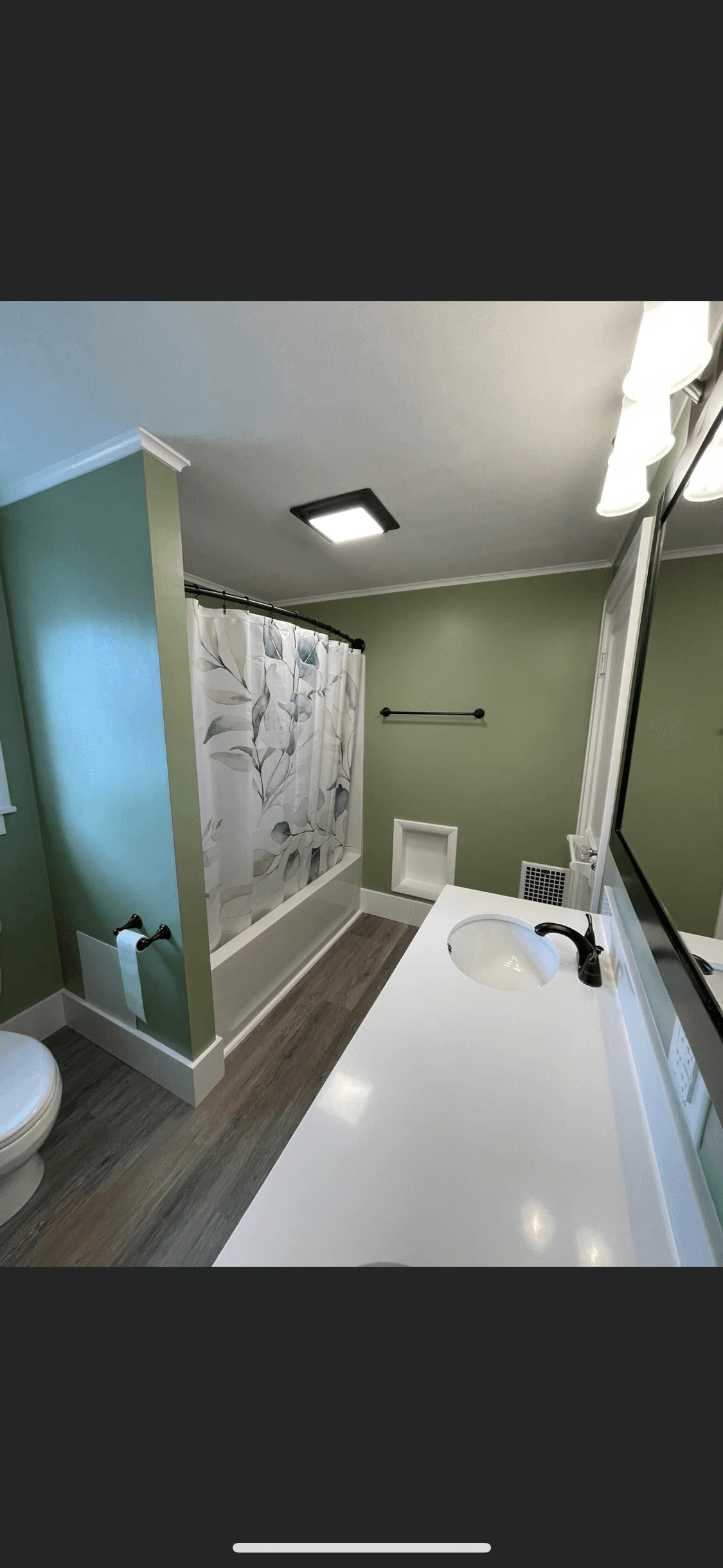 Modern bathroom with sage green walls, white vanity, and floral shower curtain