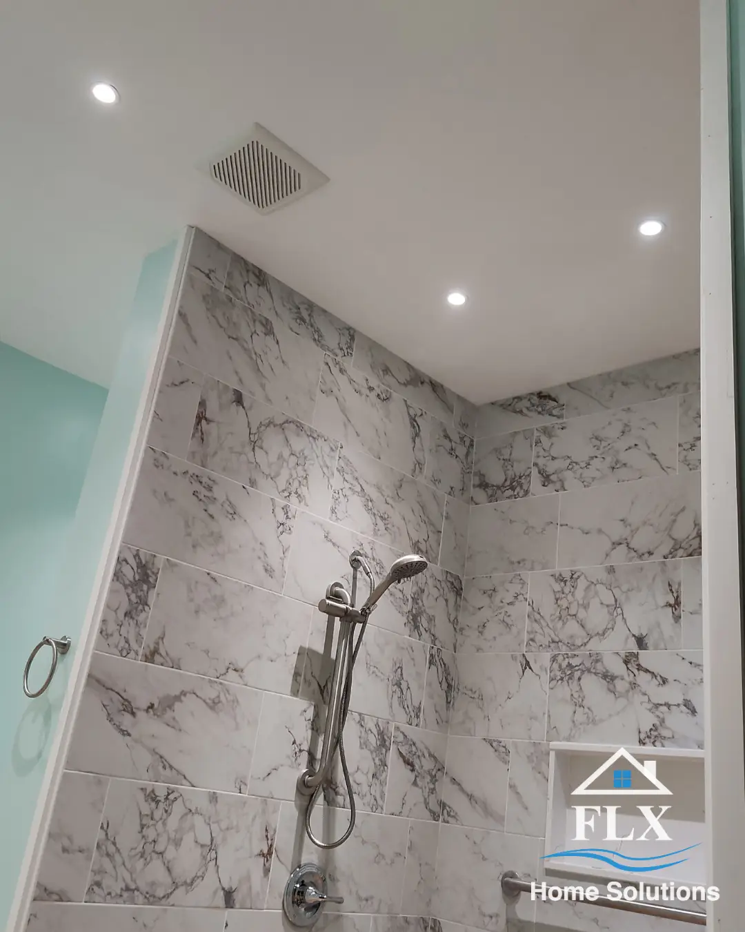 Walk-in shower ceiling with recessed lighting, exhaust fan, and marble tile walls