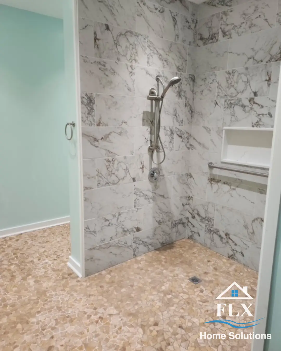Walk-in shower with marble tile walls, handheld showerhead, and built-in niche
