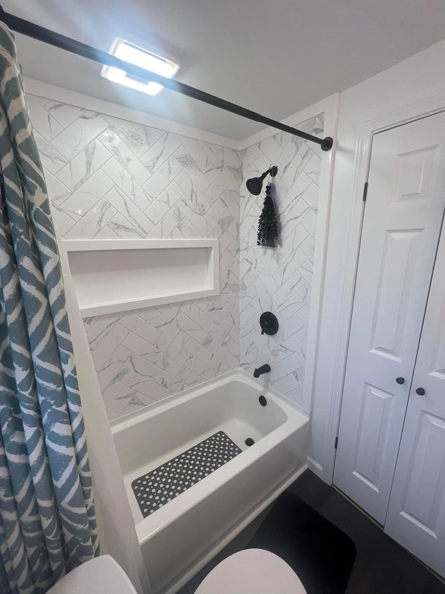 White marble herringbone tile bathroom with built-in tub and black fixtures