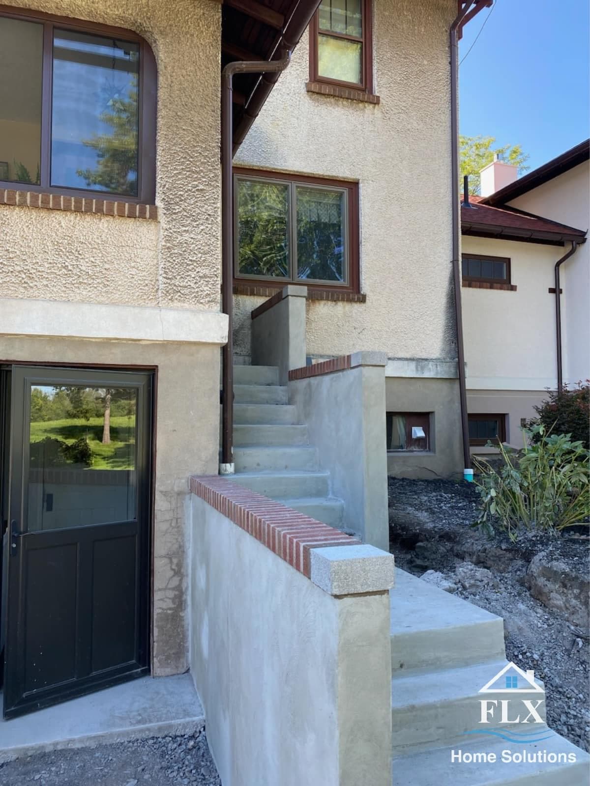 Concrete stairs leading to house entrance with brick accent trim