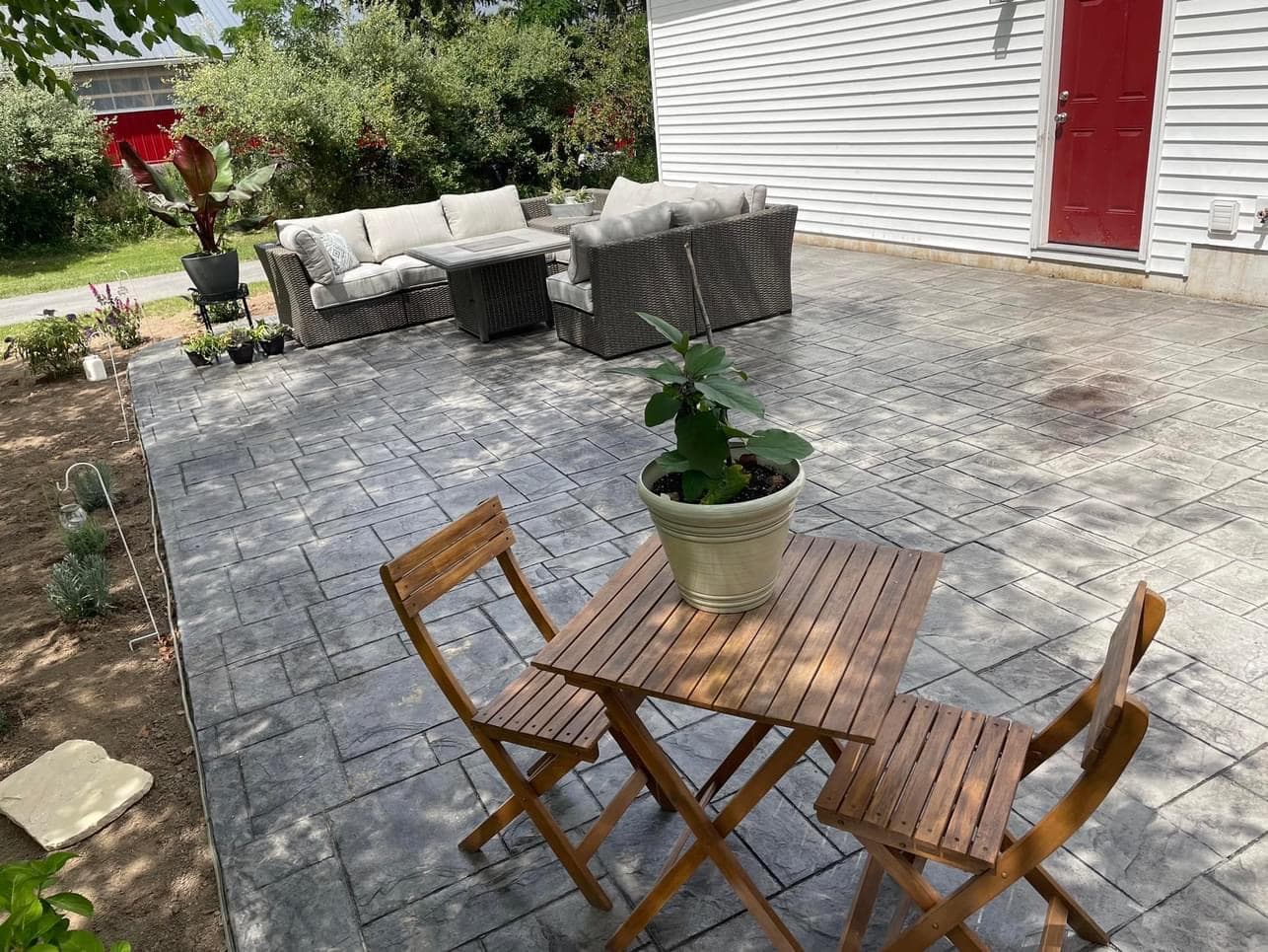 Concrete paver patio with outdoor seating areas and white siding house