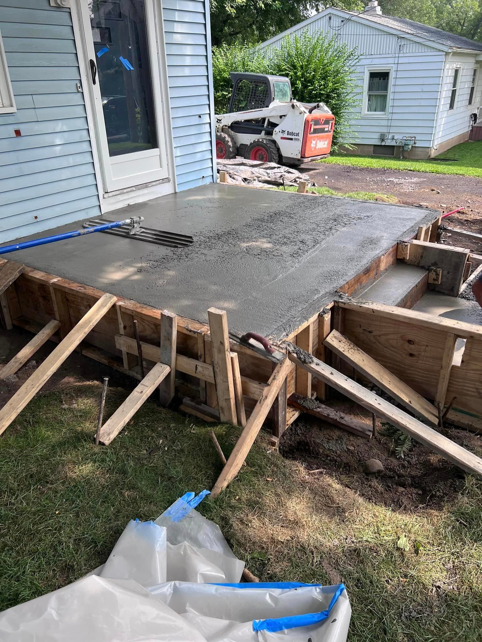 Fresh concrete poured into wooden forms for new patio construction