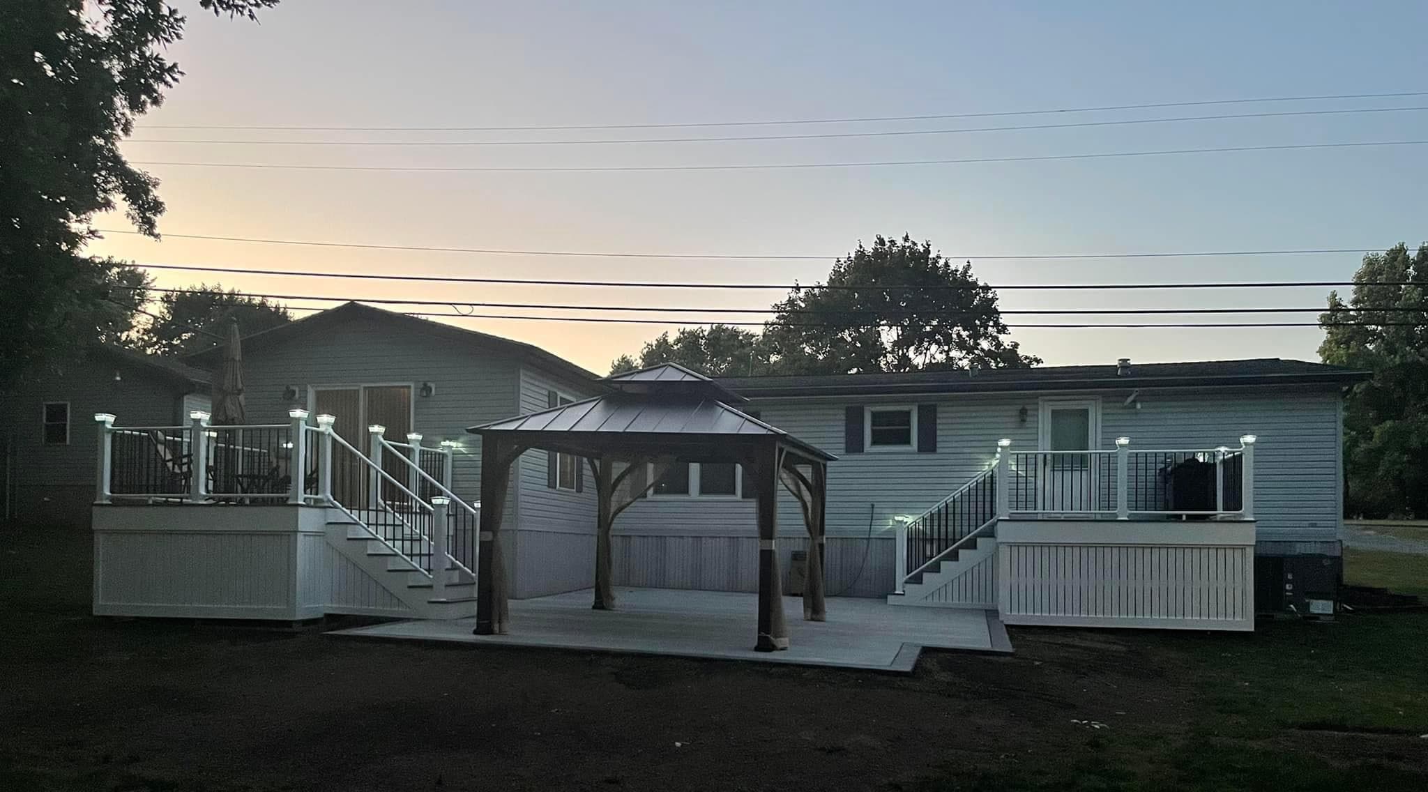 Concrete patio with wooden gazebo between two mobile homes at dusk