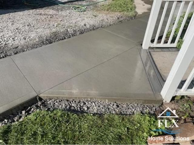 Concrete sidewalk and porch entry with white railing and gravel border