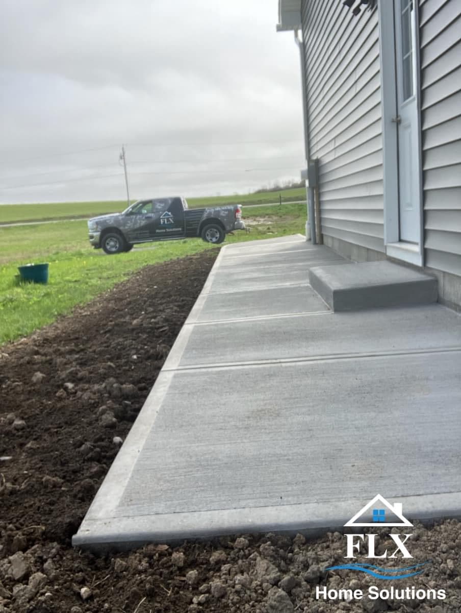Newly poured concrete sidewalk along house with company truck parked in yard