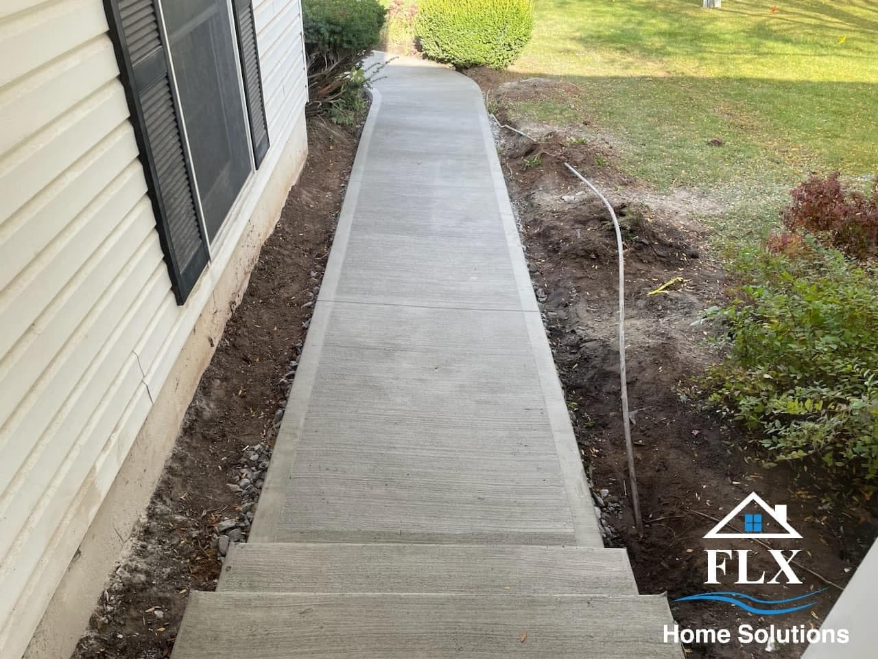 Freshly poured concrete sidewalk alongside house with brushed finish