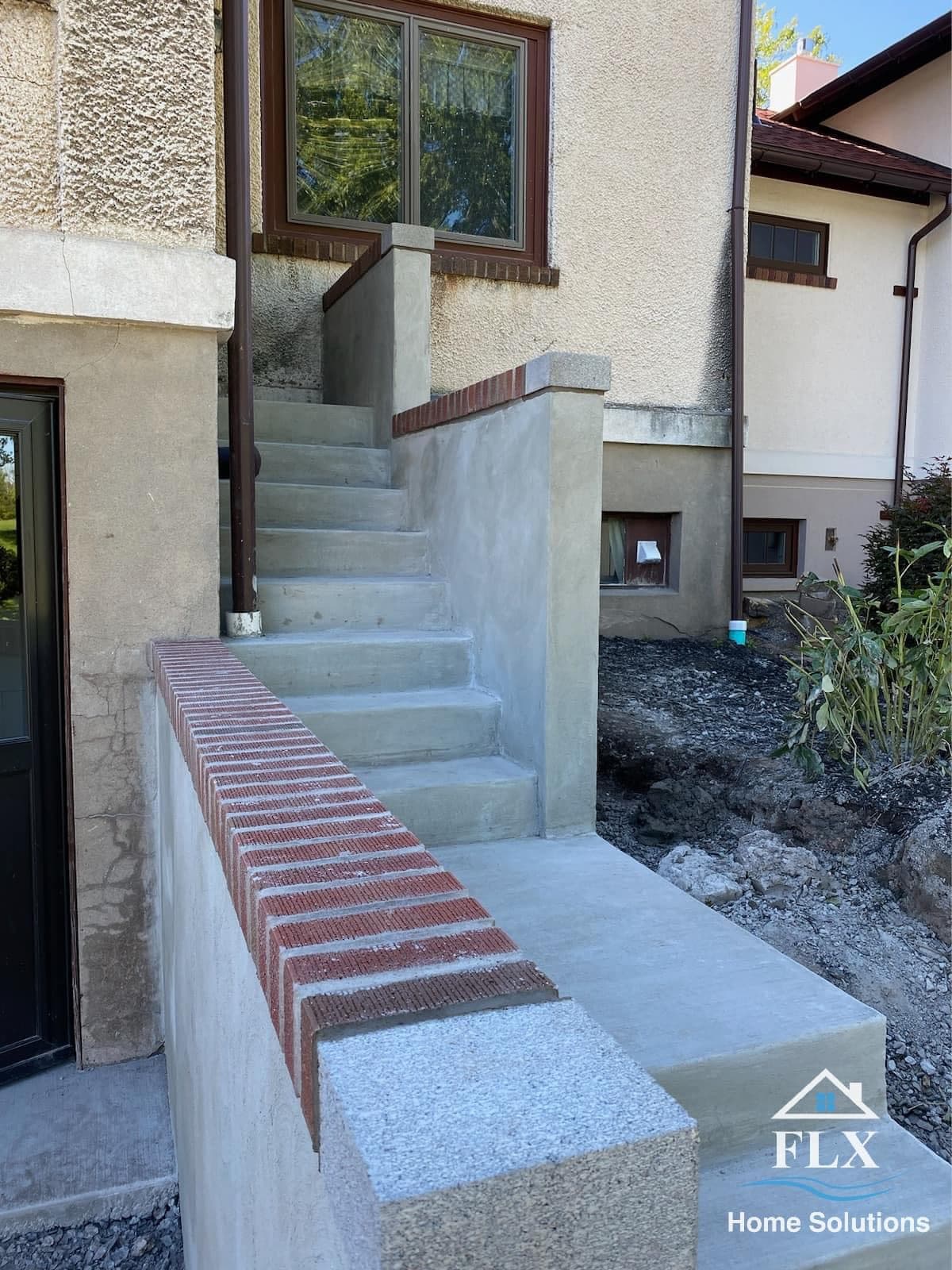 Concrete stairway with red brick treads leading to home entrance