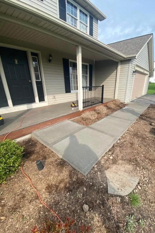 Concrete walkway leading to covered front porch with blue door