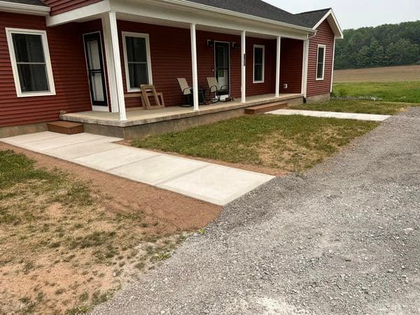Concrete walkway leading to covered porch of red siding house