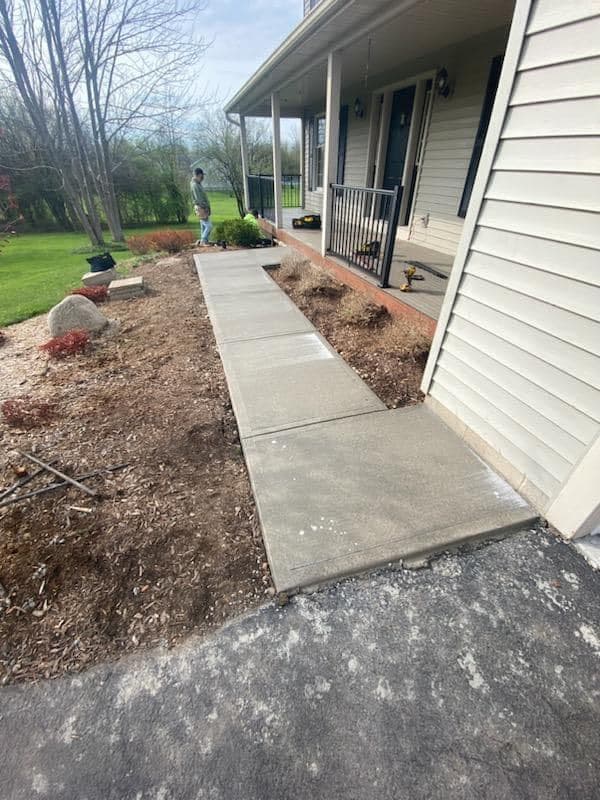 New concrete walkway leading to white house with covered porch