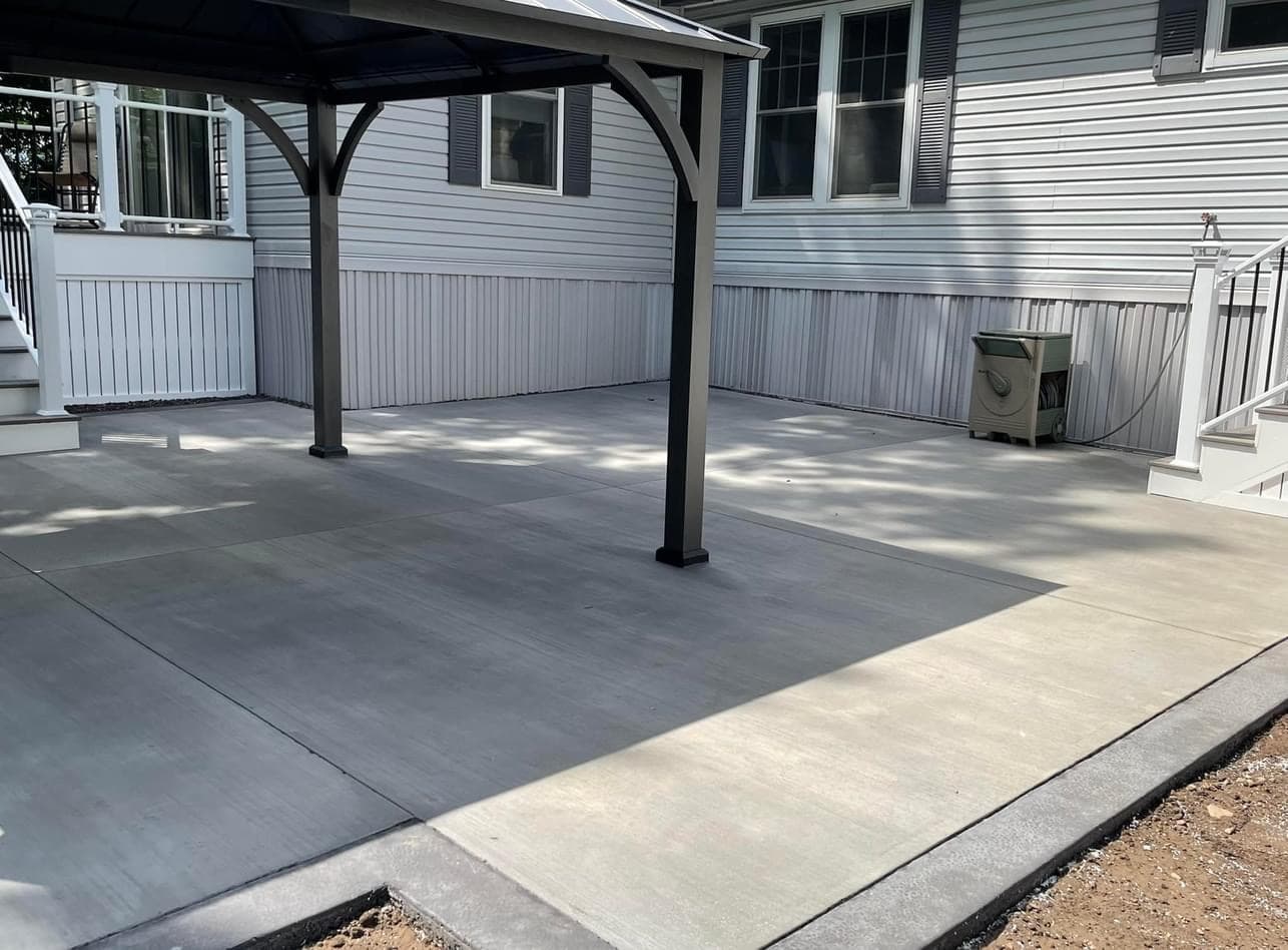 Covered patio with gray concrete flooring and white vinyl skirting