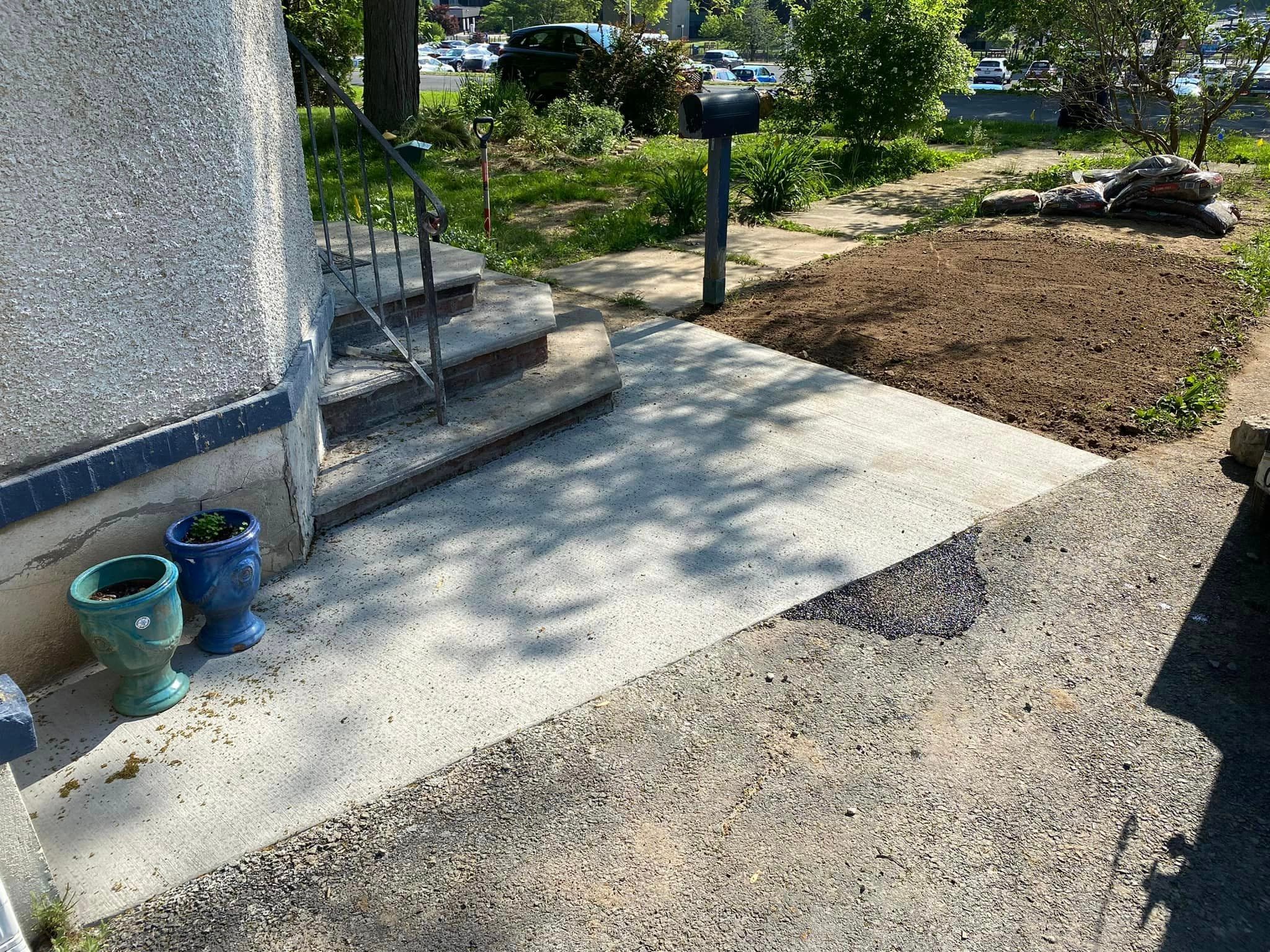 Cracked and damaged concrete walkway with steps leading to house entrance