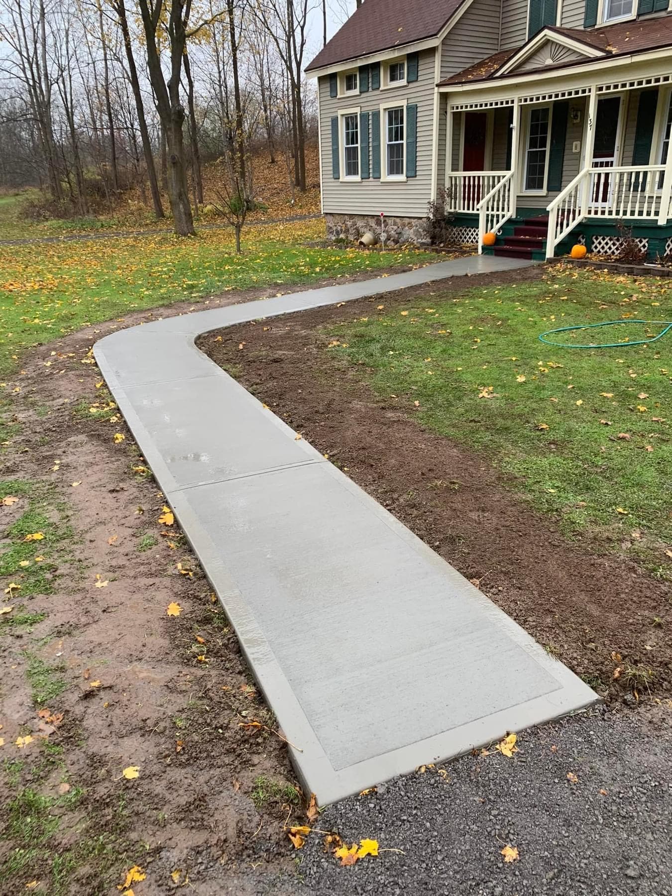 Newly installed curved concrete walkway leading to front porch of house