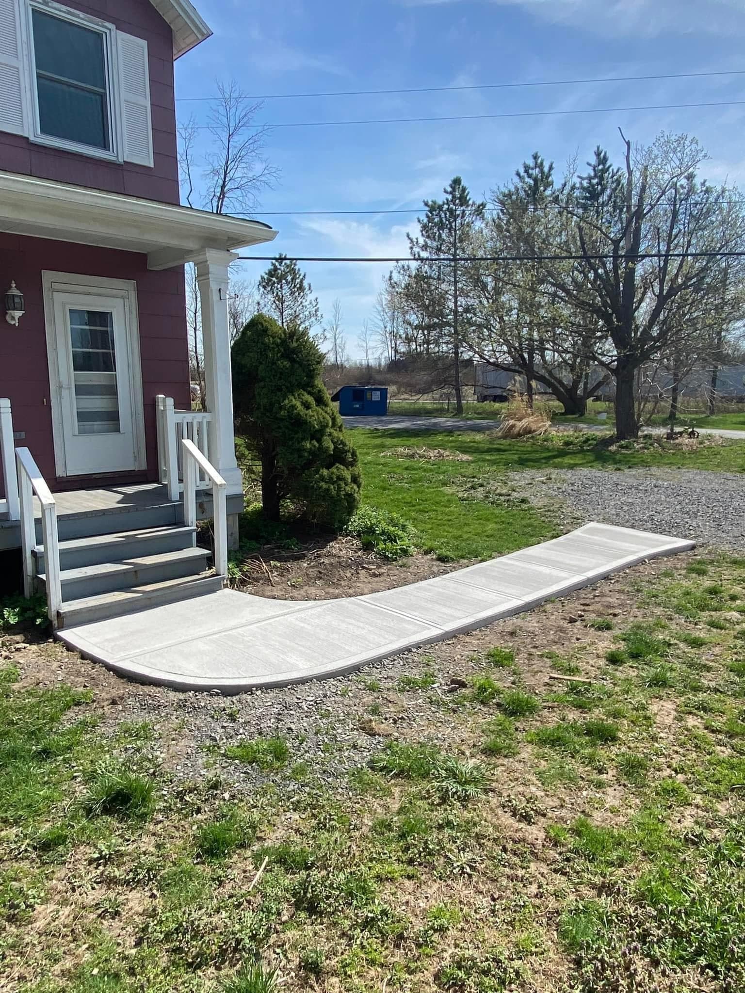 Curved concrete walkway leading from home entrance with white railings