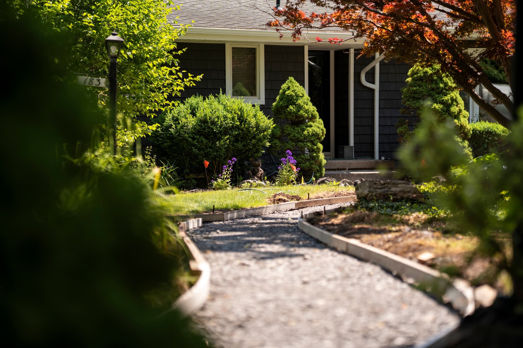 Curved concrete walkway leading to house entrance with landscaped yard