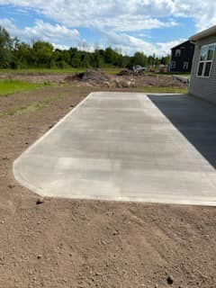 Newly poured concrete driveway apron extending from house foundation
