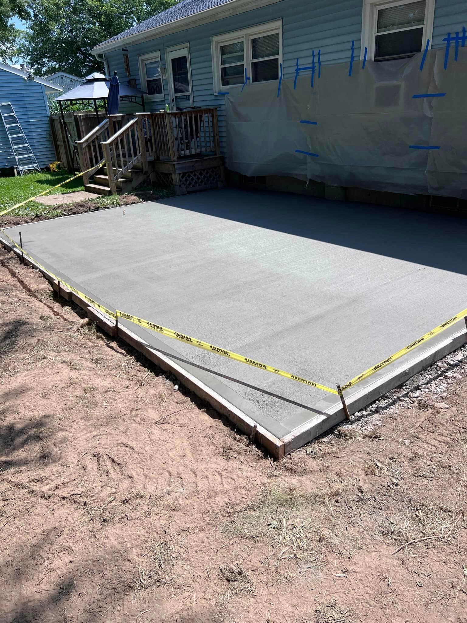 Freshly poured concrete patio with yellow caution tape around edges