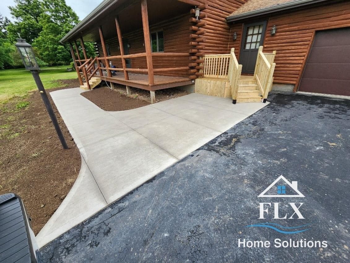 Concrete walkway leading to rustic log cabin with wooden porch and steps