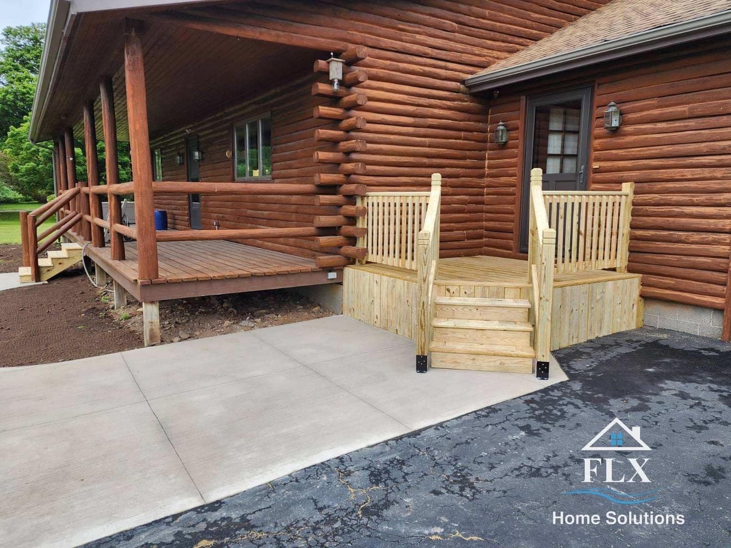 New concrete pad with wooden stairs leading to log cabin entrance