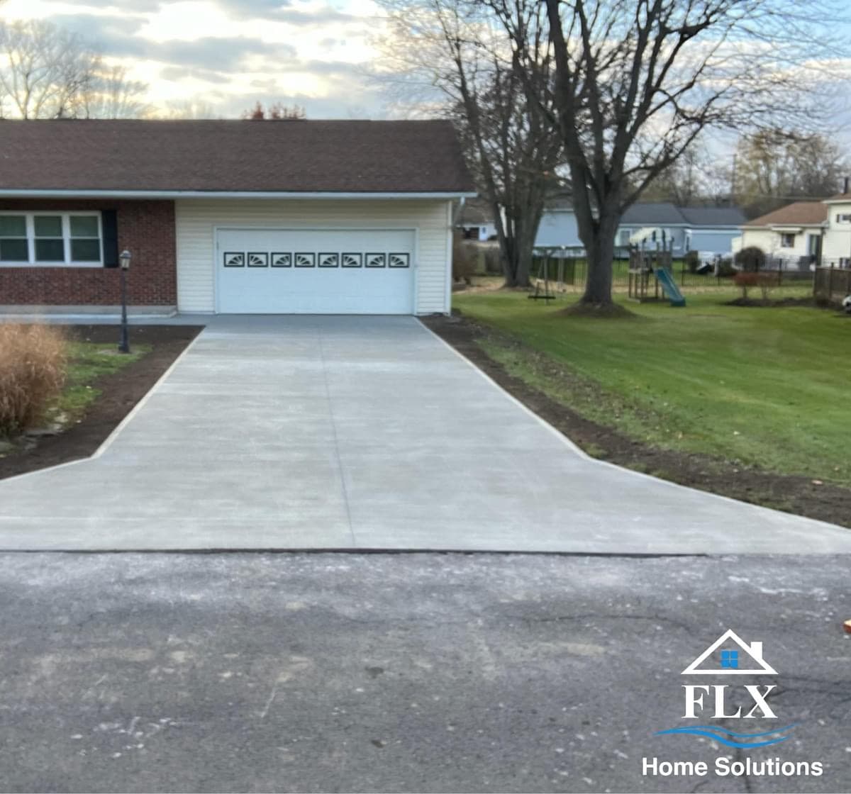 Newly poured concrete driveway leading to garage with branching walkway