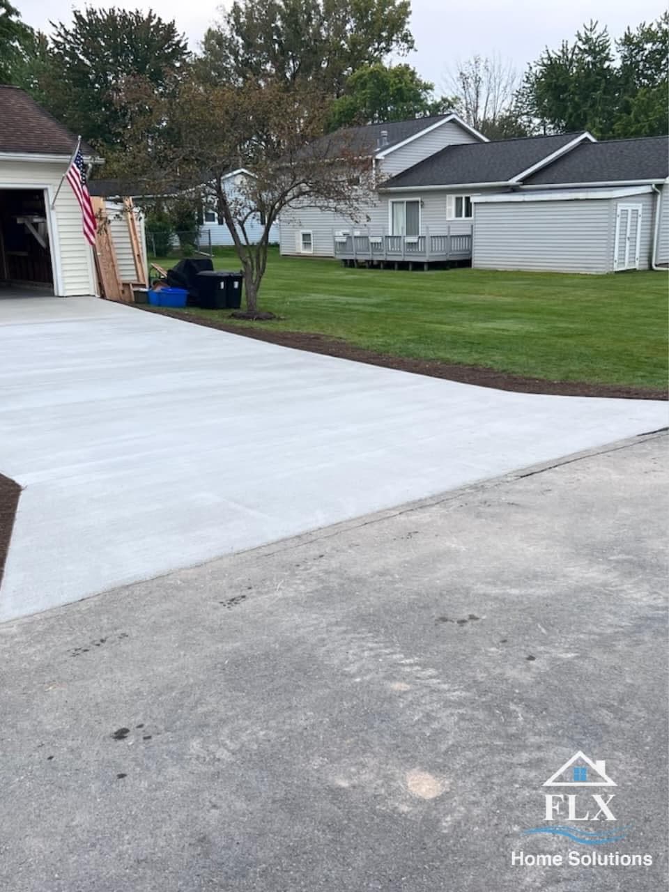 Newly poured concrete driveway extension next to existing driveway with residential homes in background