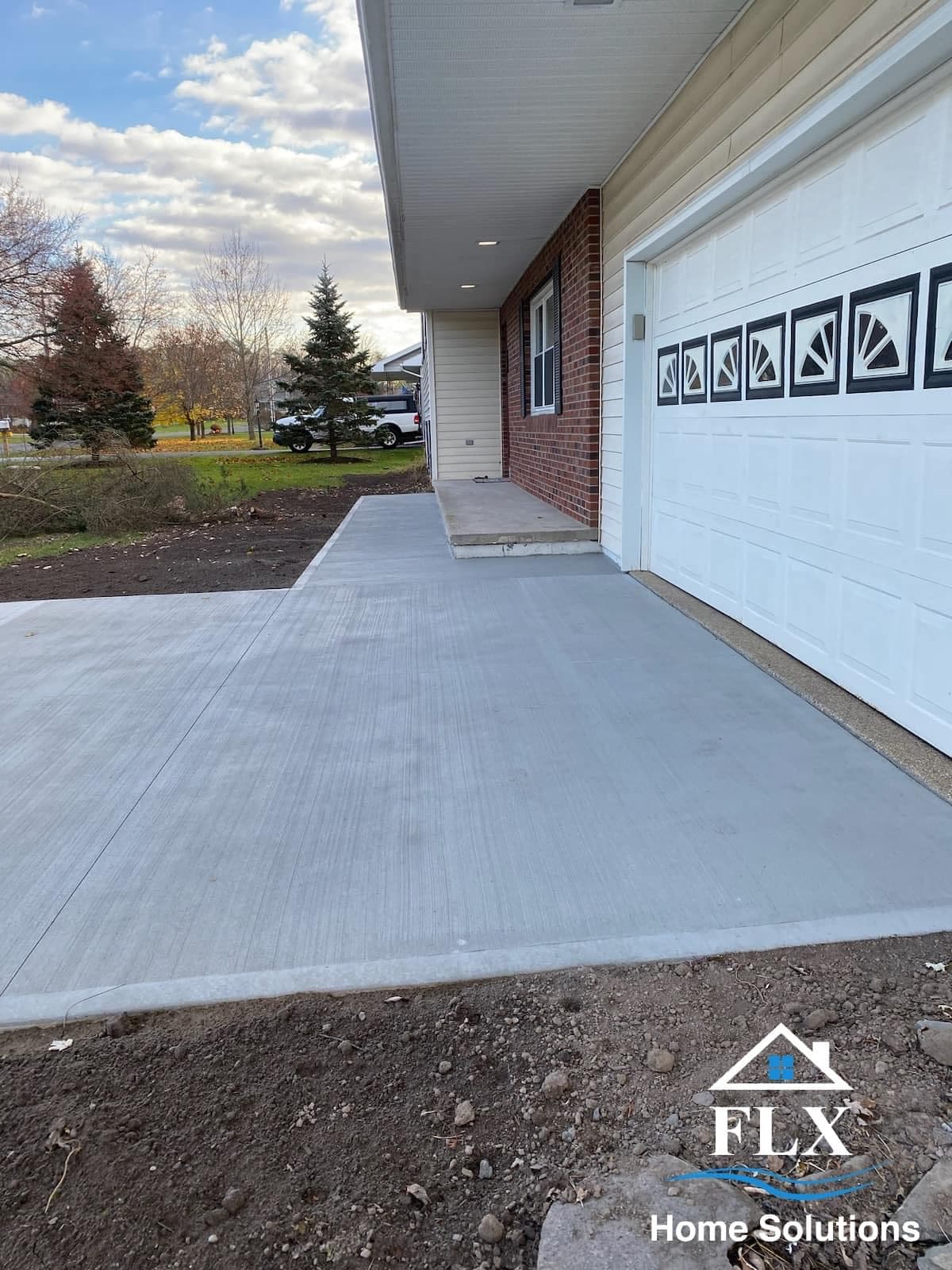 Freshly poured concrete driveway leading to residential garage with decorative doors