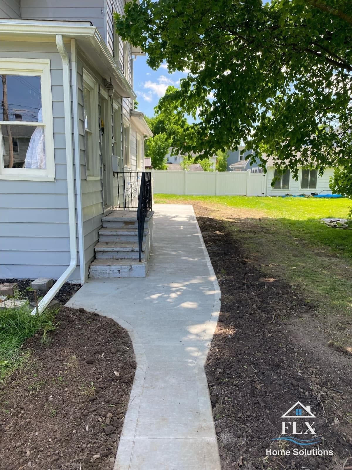 Newly poured concrete sidewalk leading from house steps to backyard