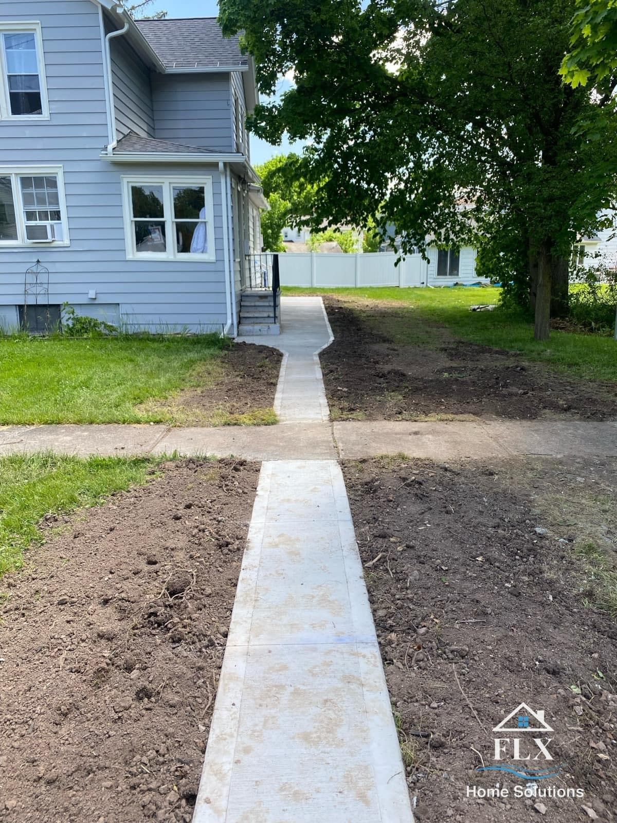 Freshly poured concrete sidewalk leading to gray house side entrance