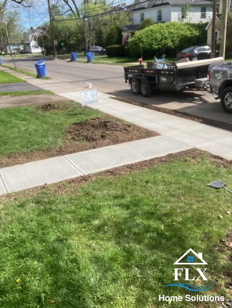 Freshly installed concrete sidewalk sections with work truck and yard sign in residential neighborhood