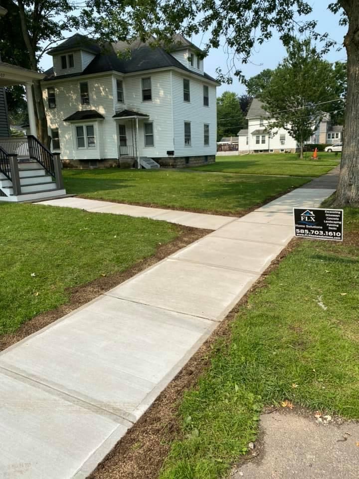 Newly poured concrete sidewalk leading to white two-story house with FLX Home Solutions sign