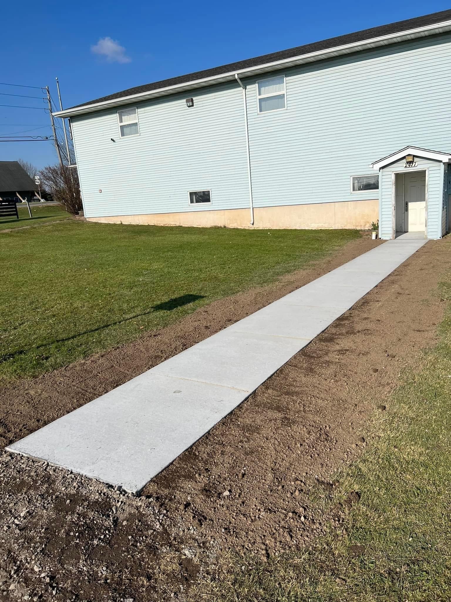 New concrete sidewalk leading to side entrance of light blue house