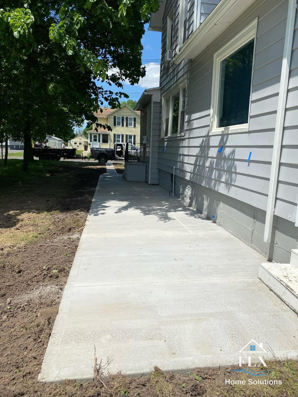Freshly poured concrete sidewalk along gray house exterior