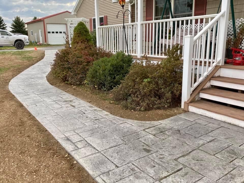 Curved paver stone walkway leading to house entrance with white railing