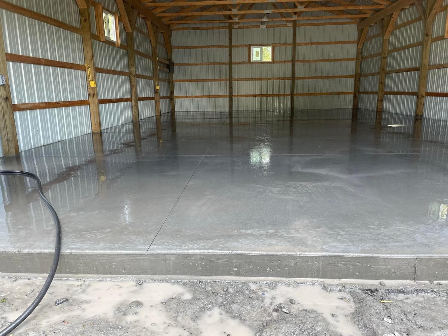 Freshly poured concrete floor in post-frame barn with metal siding