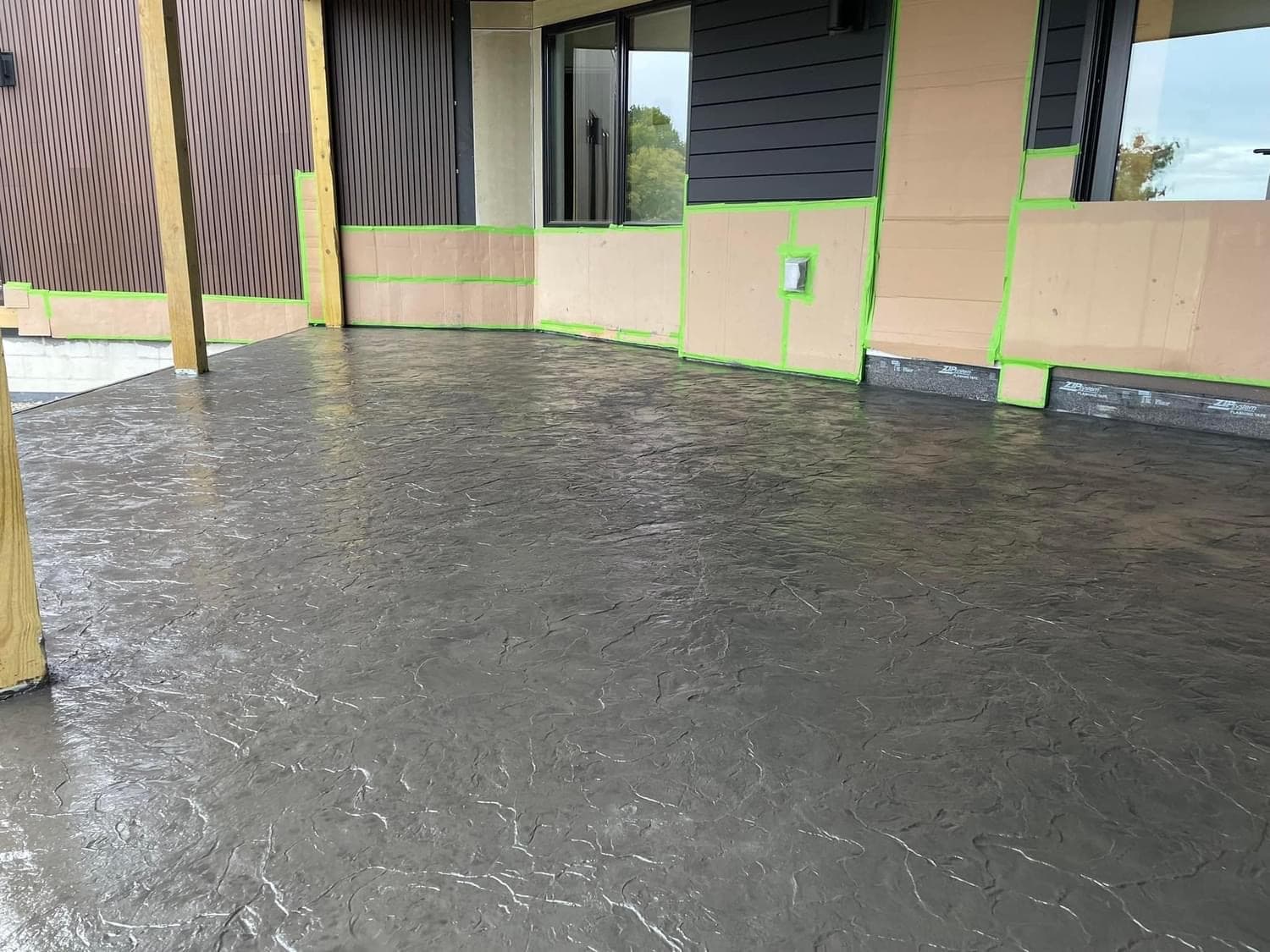 Gray stamped concrete floor during construction with green taped walls