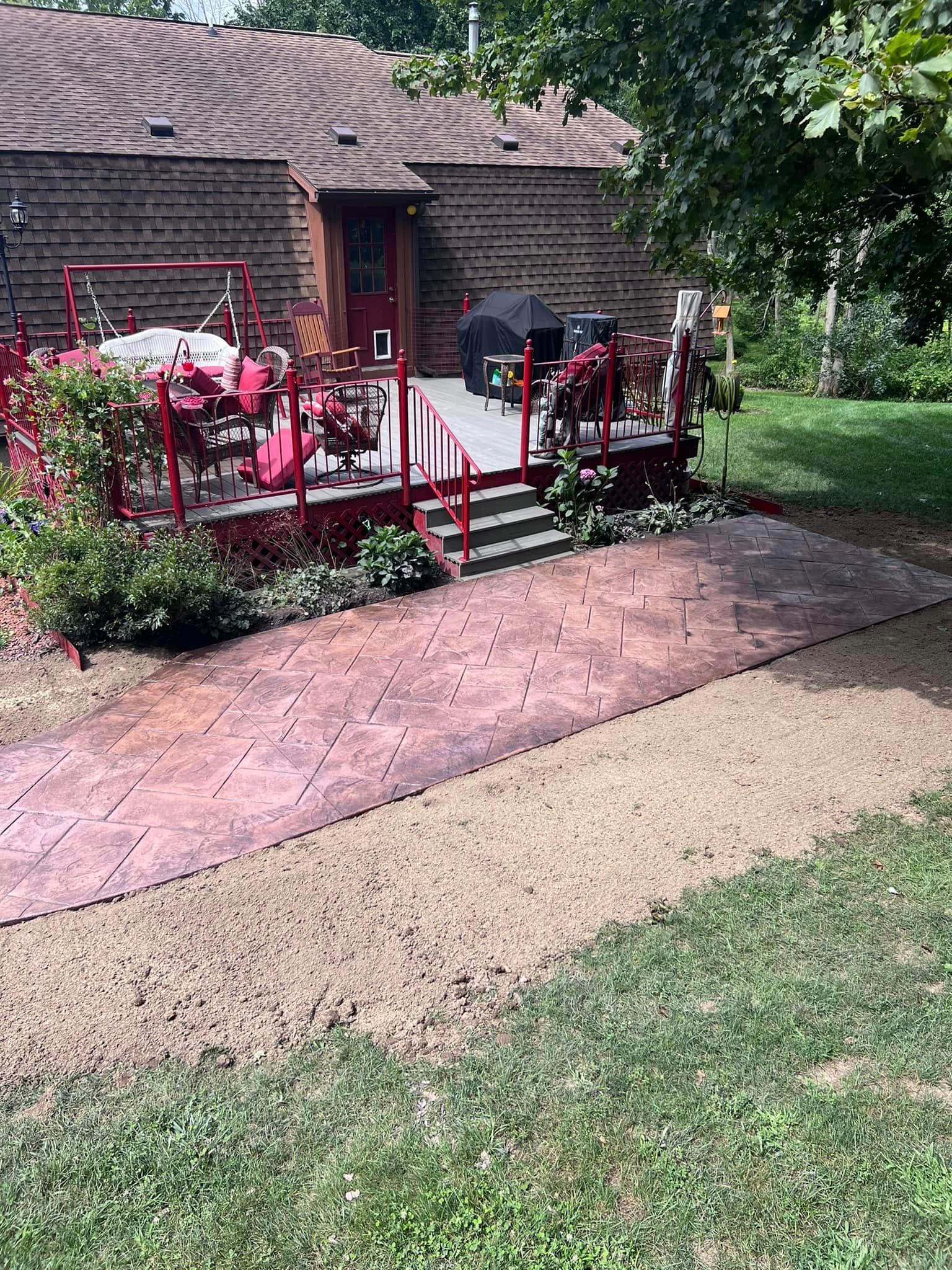 Stamped concrete patio leading to red-painted deck with outdoor furniture