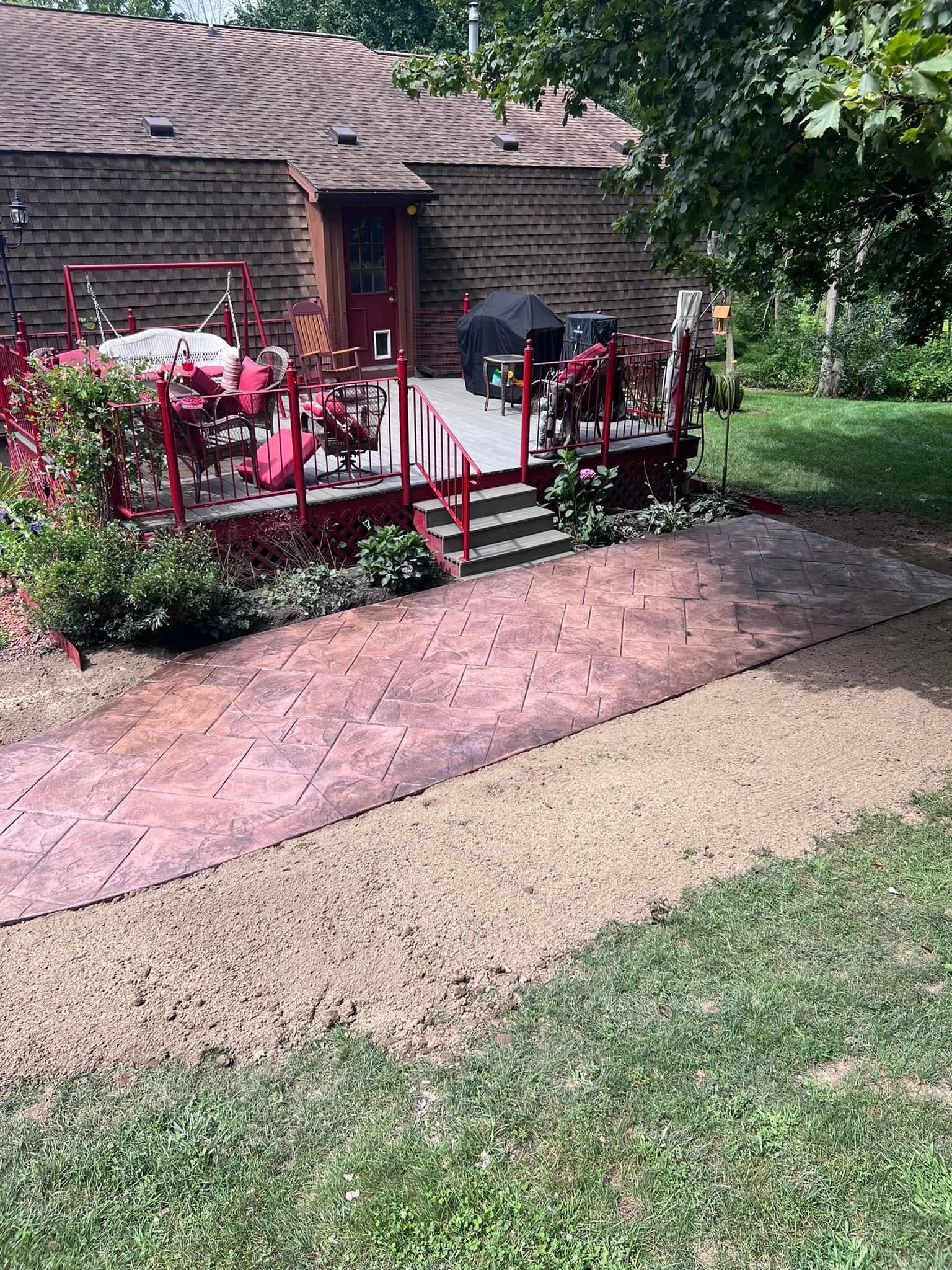 Stamped concrete patio leading to red deck with covered grill area